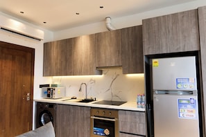 Una cucina moderna con lavatrice integrata, forno, frigorifero, lavello e pensili in legno.