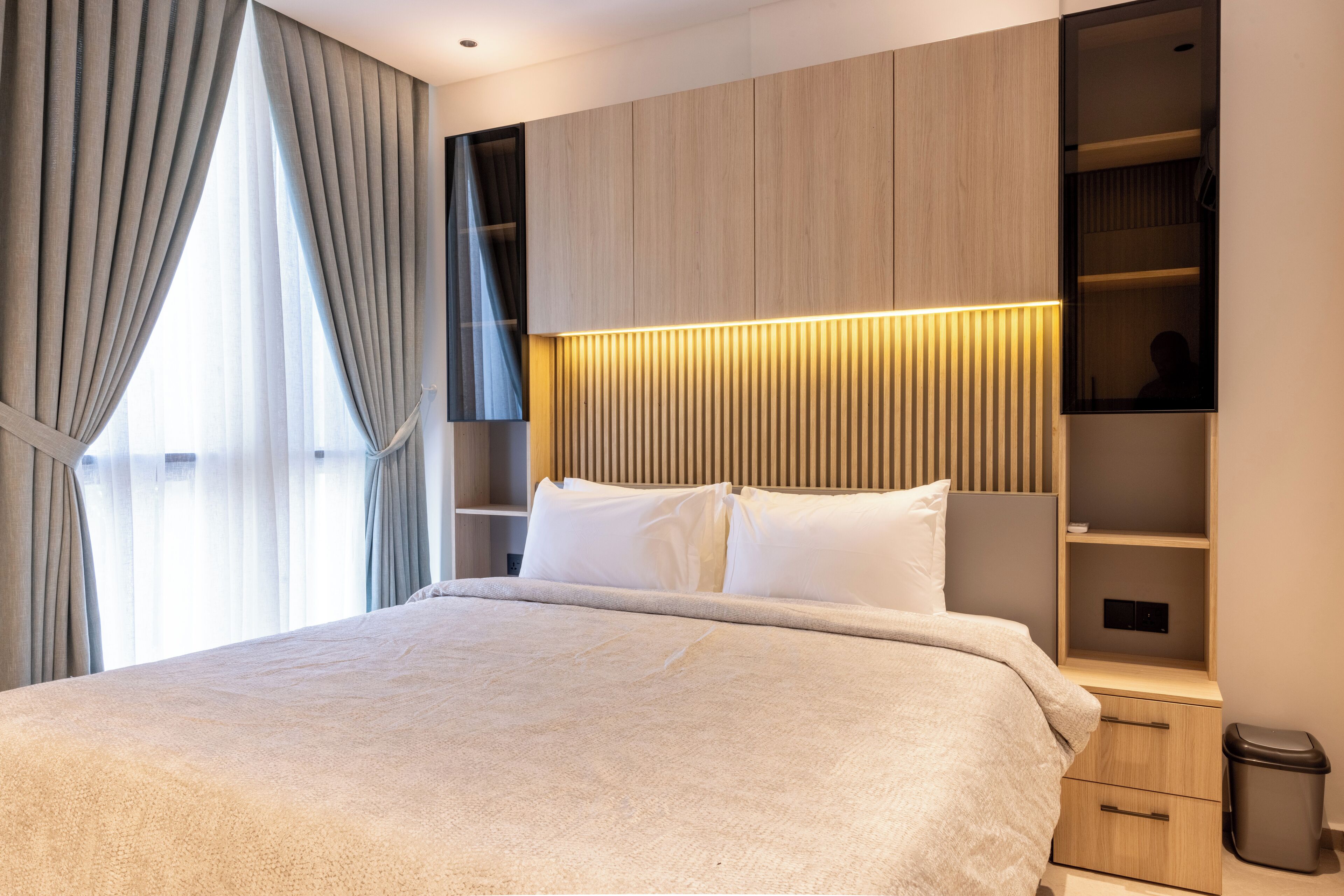 Ein modernes Schlafzimmer mit einem großen Bett, eingebauten Regalen und einem Nachttisch.