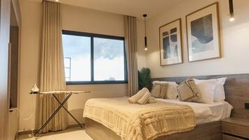 Un dormitorio con cama, cortinas, una ventana y cuadros en la pared.