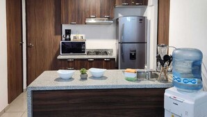Una cocina moderna con armarios de madera oscura, un refrigerador de acero inoxidable, un microondas y un dispensador de agua.