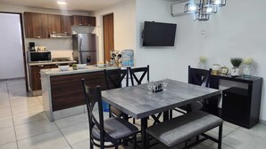 Una cocina moderna con armarios de madera oscura, microondas integrado y refrigerador de acero inoxidable.
