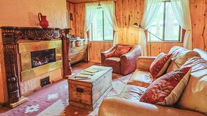Ein gemütliches Blockhaus-Interieur mit Kamin, Ledersofa und Holzwänden.