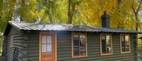 A log cabin with a wooden door, windows, and a chimney.