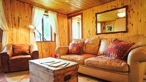 Ein gemütliches Holzhaus-Interieur mit Ledersofa, Holzschrank und Spiegel an der Wand.