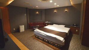 Una habitación de hotel con una cama grande, un sofá rojo, una mesita y un calentador de pared.