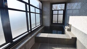 Un baño moderno con ventanas amplias, una bañera empotrada y una pared de piedra.