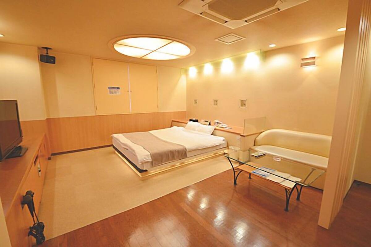 A hotel room with a bed, bedside table, lamp, and a sofa.