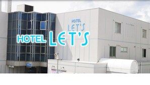 Un edificio de hotel con un letrero que dice "HOTEL LET'S" y una amplia estructura de ventanales.