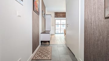 A hallway with a patterned rug, a white cabinet, and a door leading to a room with a view.
