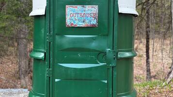 Un petit bâtiment vert servant de toilettes, avec un toit blanc et une pancarte indiquant « TOILETTES ».