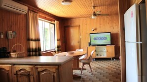 A wooden interior with a kitchen area, a dining table, chairs, a television displaying 'Scott's Own Vacation House,' and a refrigerator. - Perfect for a retreat or a short stay. Spacious living with clean fresh air. (Willunga)
