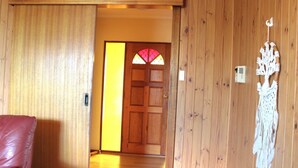 A wooden interior with a door leading to a room, a wall-mounted air conditioning unit, and a macrame decoration. - Perfect for a retreat or a short stay. Spacious living with clean fresh air. (Willunga)