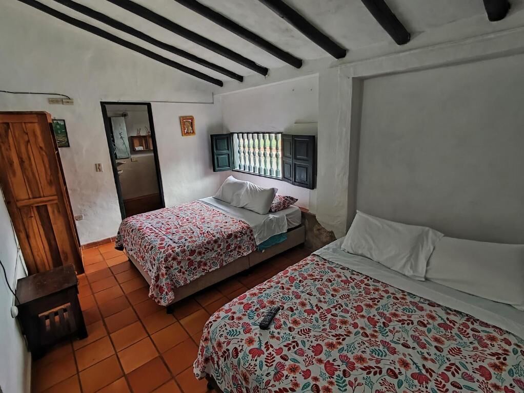 A bedroom with two beds, a wooden wardrobe, and a tiled floor.