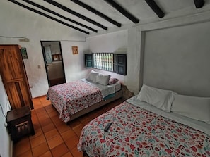 A bedroom with two beds, a wooden wardrobe, and a tiled floor.