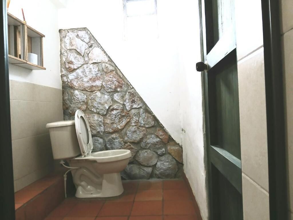 Ein Badezimmer mit einer Wand aus Steinplatten, einer Toilette und einem Fenster.