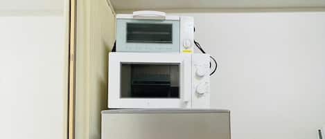 Una habitación compacta con un refrigerador de acero inoxidable y un microondas encima.