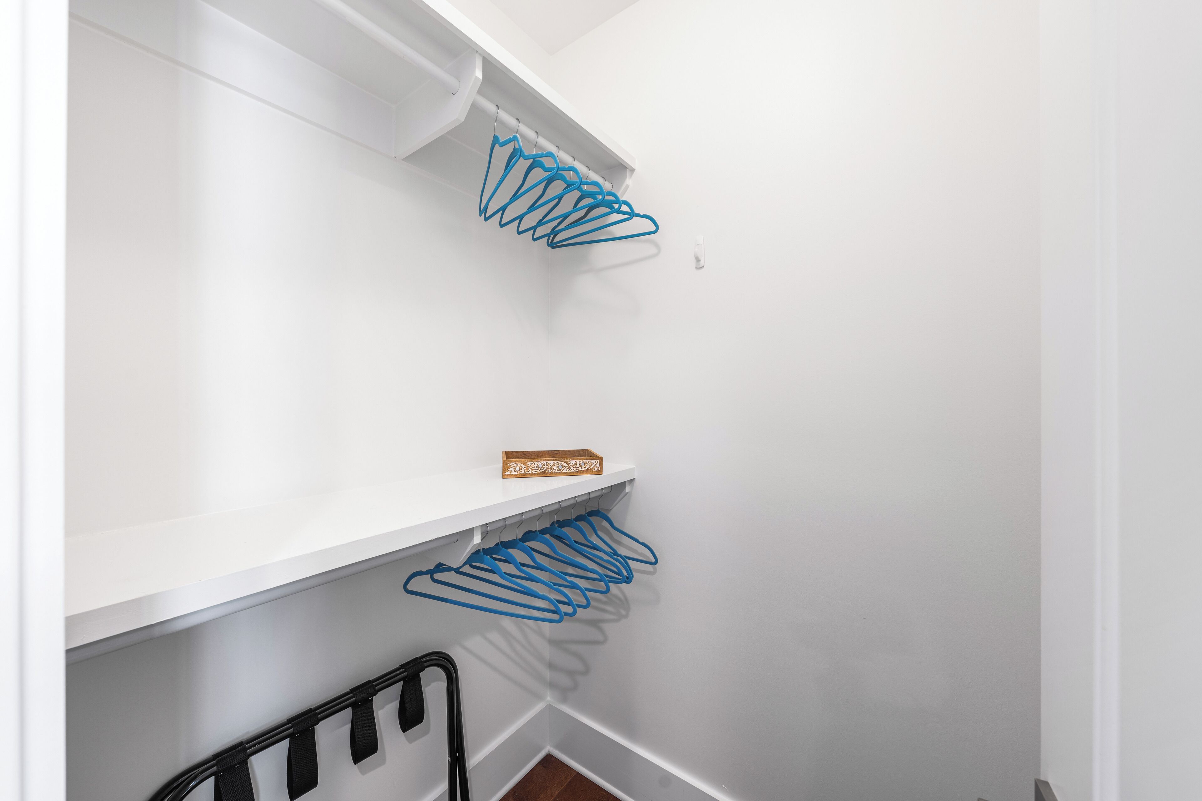 Een witte kast met blauwe ophanghaakjes en een zwarte metalen rek.