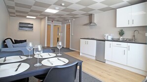 A modern kitchen with white cabinets, a stainless steel sink, and a countertop with a coffee maker and a plant.