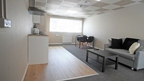 A modern apartment with a kitchenette, a dining area, and a living room with a sofa and coffee table.