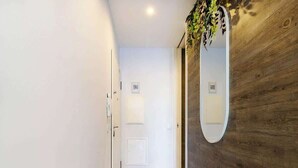 Un pasillo con pared de madera, una puerta blanca y un espejo.