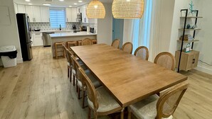 Eine moderne Küche mit weißen Schränken, einem Holzespeisetisch und einer hängenden Rattanleuchte.