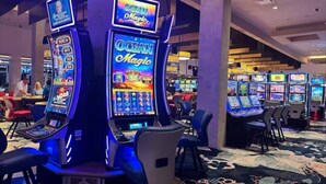 Ein Casino-Bereich mit mehreren Ocean Magic Spielautomaten, Sitzen und einem Teppichboden.