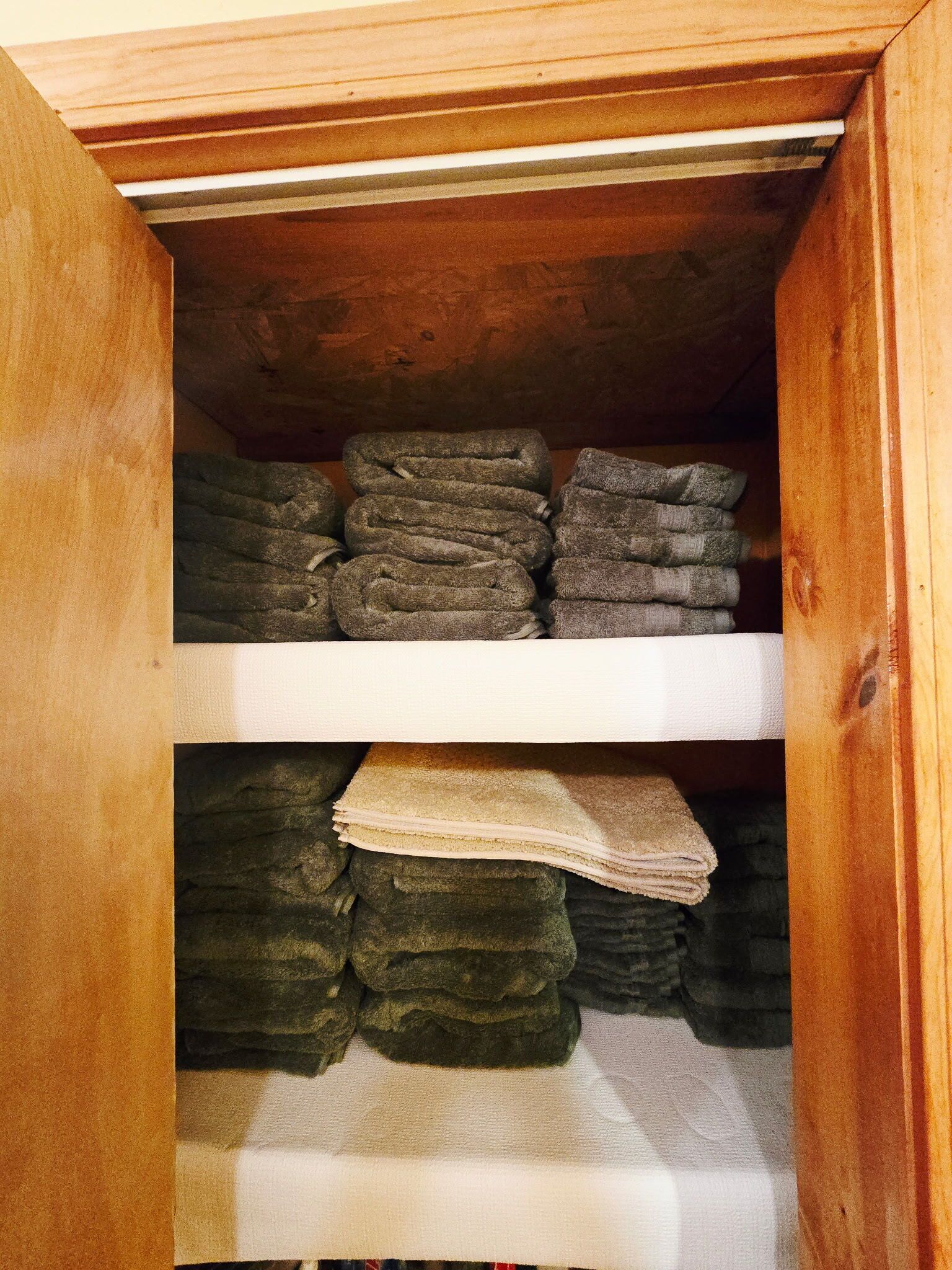 Puisesta kaapista, jossa on kaksi hyllyä, löytyy siististi taiteltuja pyyhkeitä.