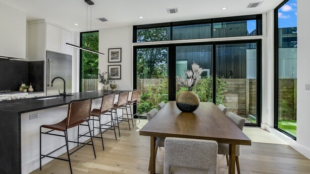 A modern kitchen with a central island, bar stools, and a dining table with chairs. - Stunning Modern Zilker Home with Private Pool, Designer Touches & Prime Location (Austin)