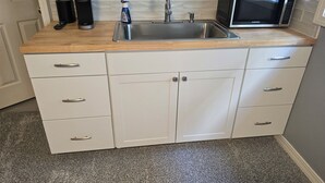 Eine Küche mit Spülbecken aus Edelstahl, einer Mikrowelle und einer Keurig-Kaffeemaschine.