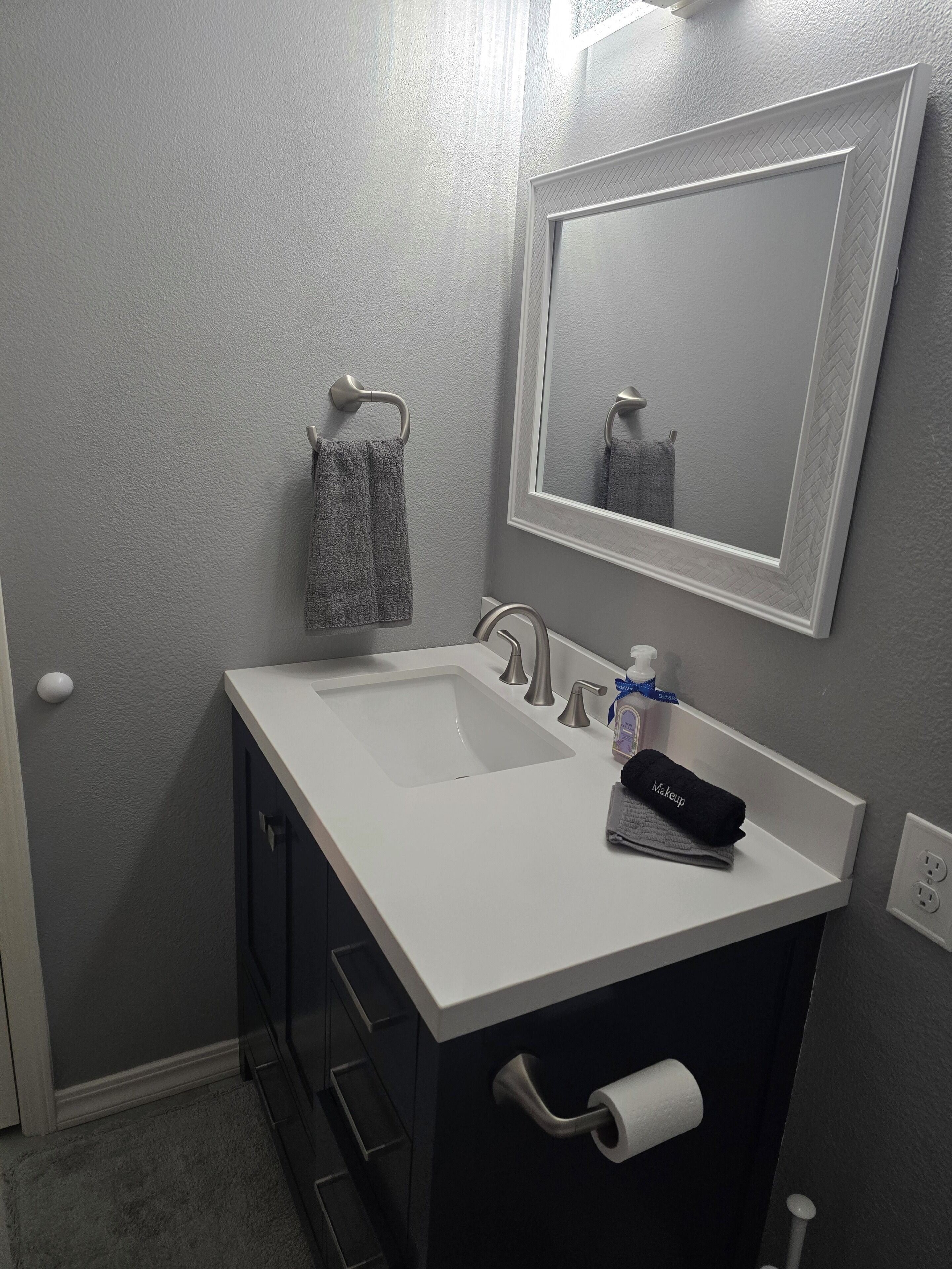 A bathroom with a white sink, a mirror, and a towel rack.