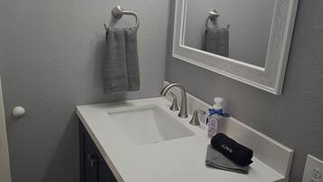 A bathroom with a white sink, a mirror, and a towel rack.