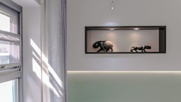 A framed artwork of two animals on a wall, a window with a view, and a green bench. - Blooming Lotus Hostel (Hangzhou)