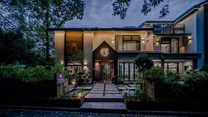 A modern building with a central entrance, surrounded by greenery and a pathway leading to the door. - Blooming Lotus Hostel (Hangzhou)