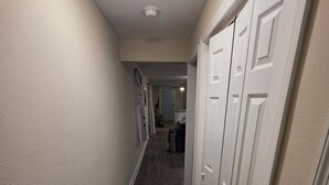 A narrow hallway with wooden flooring, white walls, and closed doors.
