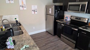A modern kitchen with stainless steel appliances, granite countertops, and dark cabinetry.