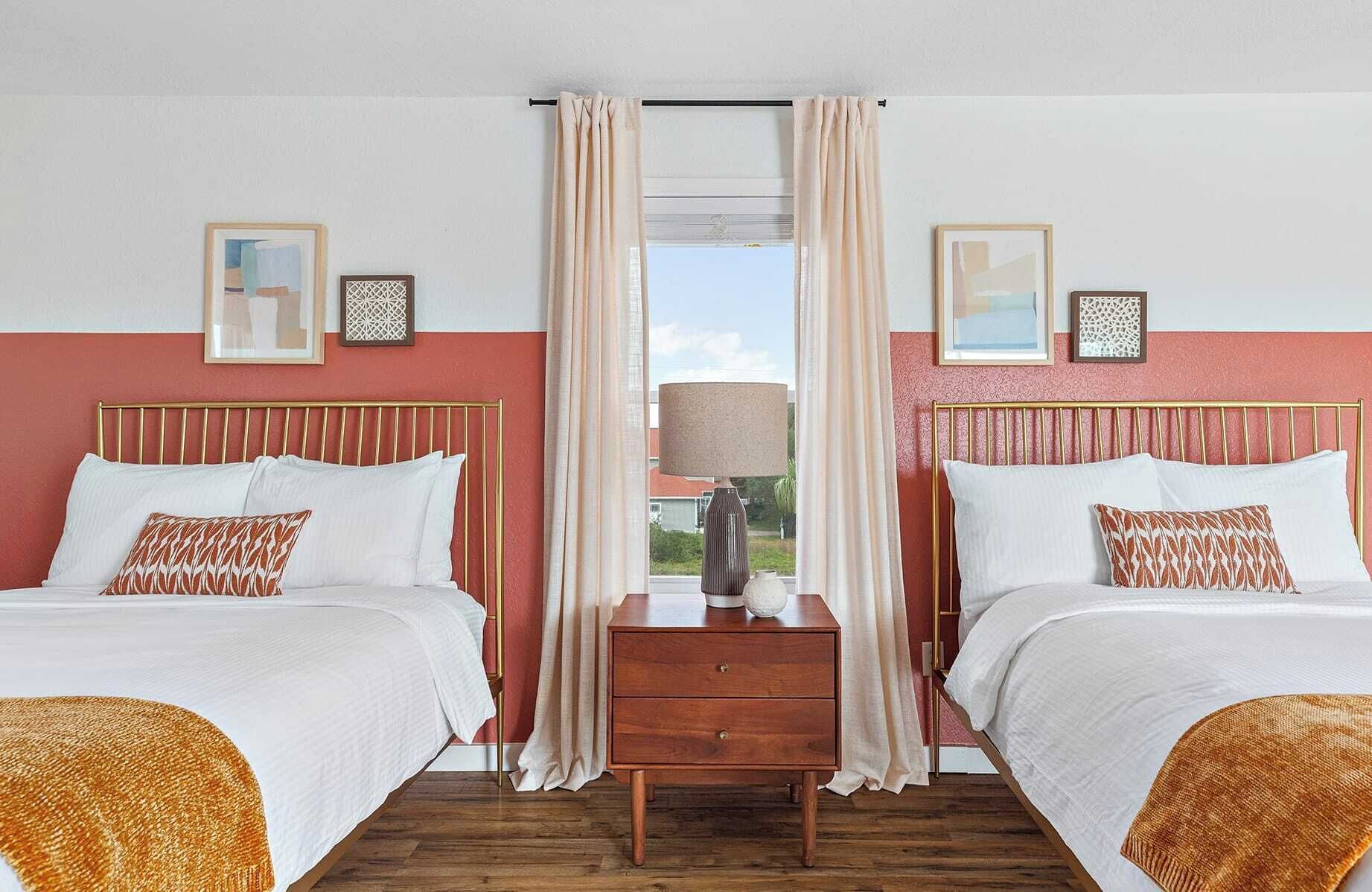 Habitación de hotel con dos camas, una mesita de noche y una ventana con cortinas.