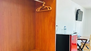 A compact room with a wooden wardrobe, a small table, and a black cabinet with a red front. - Apartment Wat Sawang Arom 08 (Koh Samui)