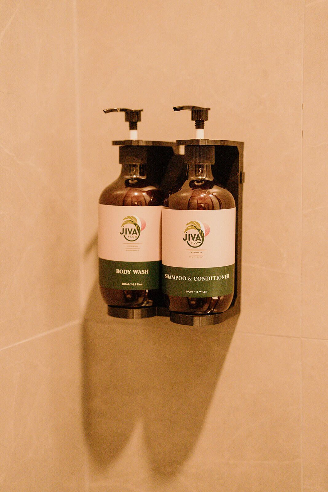 Two JIVA Flow body wash and shampoo & conditioner bottles mounted on a wall.