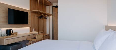 Une chambre d’hôtel comprenant un lit, un bureau avec une chaise, un téléviseur fixé au mur et une armoire.