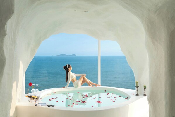 A woman sitting in a bathtub with a view of the sea. - Miyue Santorini Seaview Resort Hotel (Huizhou)