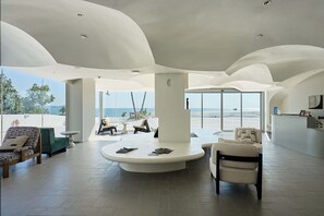 A spacious lobby with a central circular seating area, large windows offering a view of the sea, and a reception desk on the right. - Miyue Santorini Seaview Resort Hotel (Huizhou)