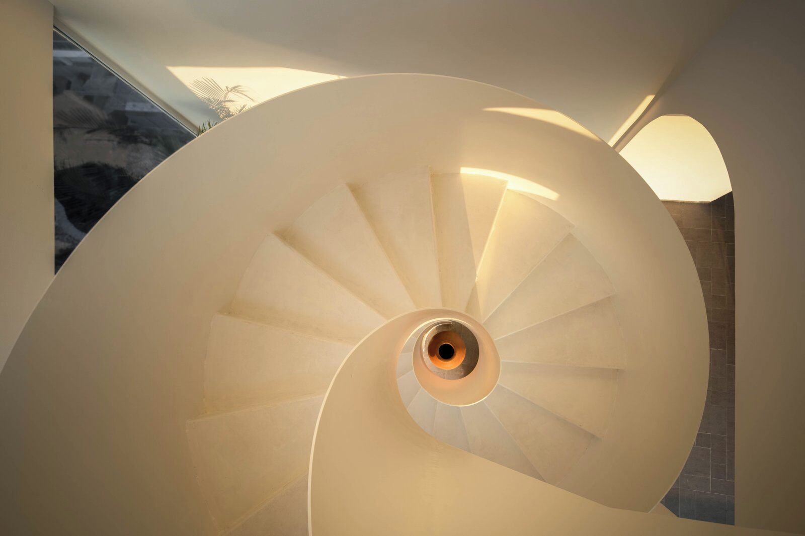 A spiral staircase with a central column and light fixtures on the walls.