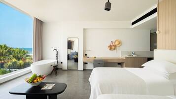 A hotel room with a large bed, a desk, a bathroom, and a view of the ocean.