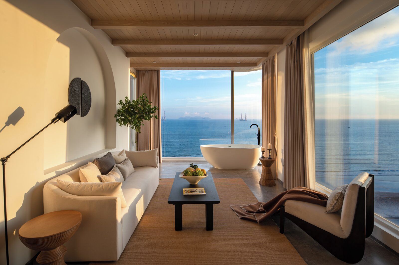 A modern living room with a large window, a bathtub, and a sofa.