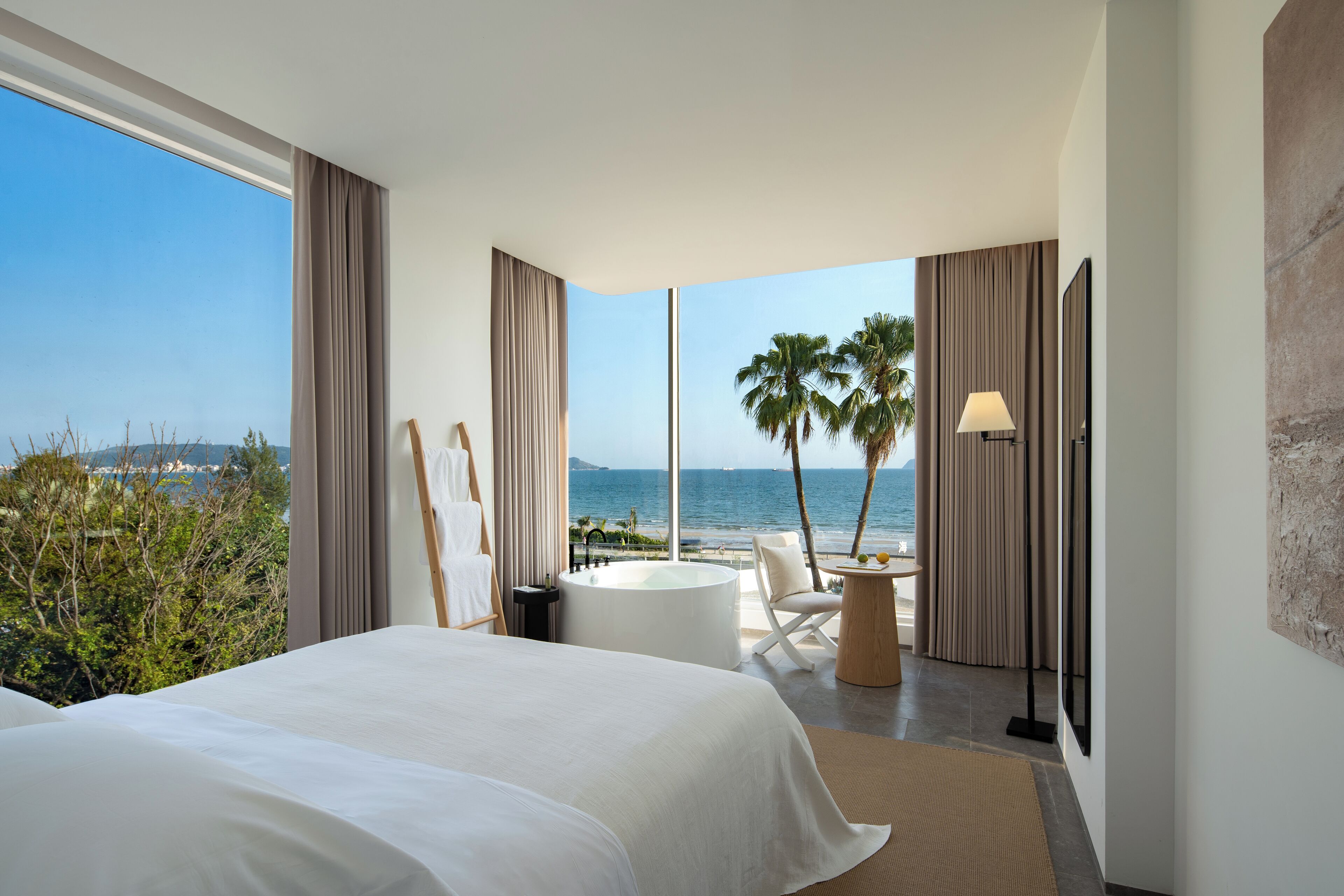 Una habitació d'hotel moderna amb un llit gran, una zona de seients amb vistes a l'oceà i una banyera.