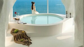 A woman in a white dress sitting by a large bathtub with a view of the sea. - Miyue Santorini Seaview Resort Hotel (Huizhou)