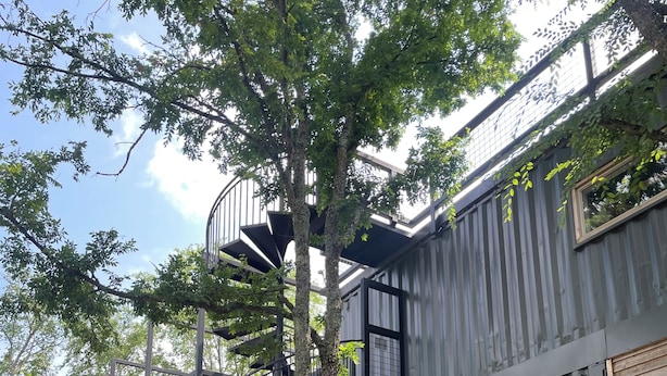 A modern building with a spiral staircase, large windows, and a stone pathway.