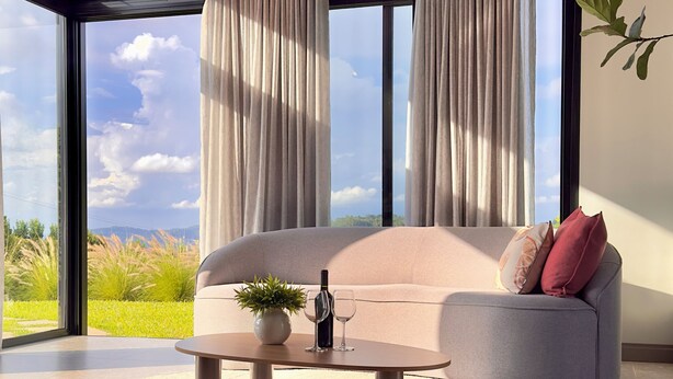 A modern living room with a large window, a sofa, a coffee table, and a plant. - Cozy house in the countryside of Garibaldi, close to wineries and restaurants (Garibaldi)