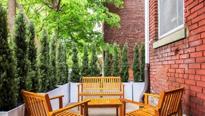 Une terrasse avec des meubles en bois et un mur en briques.