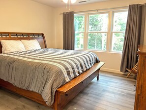 A bedroom with a wooden bed, a window with curtains, and a wooden floor. - Non-smoking lake house with private beach, dock and kayaks (Nebo)